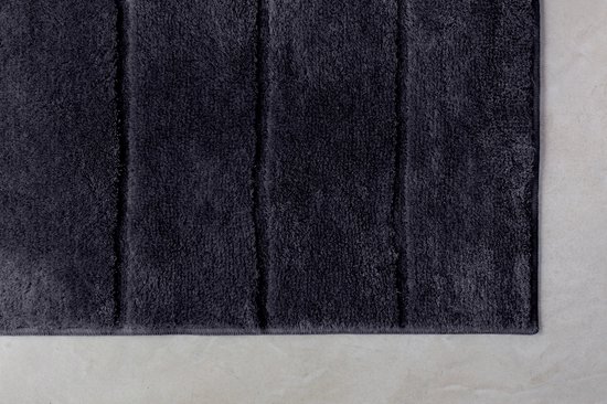 Donkergrijze badmat met verticale ribbels en een zachte, pluizige textuur.