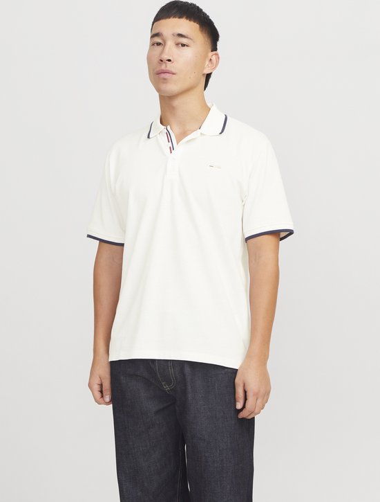Witte poloshirt met donkerblauwe bies op kraag en mouwen, gedragen door een man met spijkerbroek.
