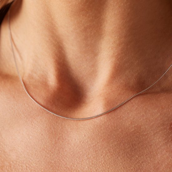 Close-up van een zilverkleurige gourmet schakelketting van 45 cm om de nek van een vrouw.