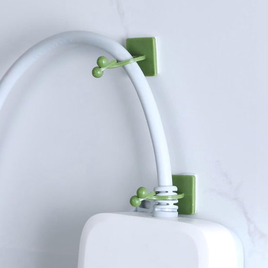 Groene clips aan een witte muur houden een witte buis vast die uit een wit apparaat komt.