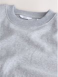Close-up van de kraag van de grijze sweater met het Next-label zichtbaar.