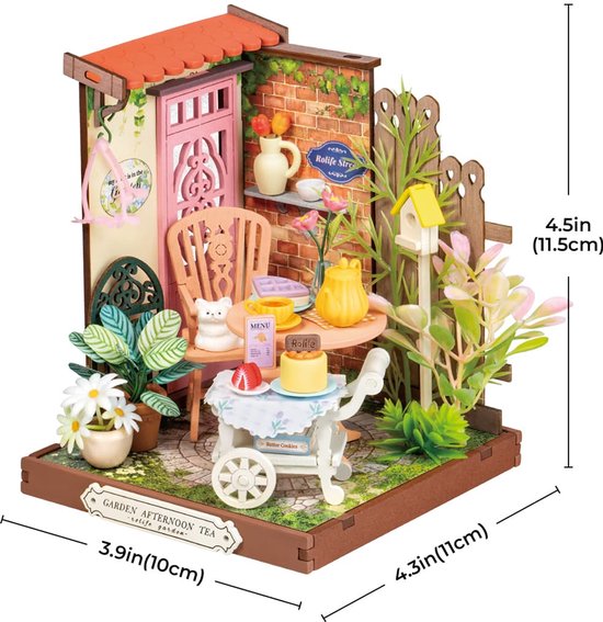 Miniatuur theeservies in een tuin met roze deur, bakstenen muur en bloemen. Afmetingen 11.5x10x11cm.