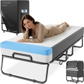 Een vrouw ligt op een uitklapbed met een matras met witte en blauwe details. Het bed is opvouwbaar met wielen en een zwarte hoes.