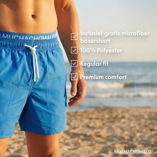 Blauwe zwembroek met 'MUCHACHOMALO' logo op de lichtblauwe tailleband en trekkoord. Achtergrond: strand en zee.
