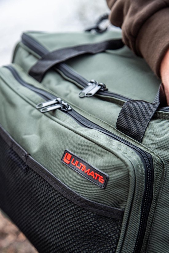 Gedetailleerde close-up van het rode 'Ultimate' logo op een groene tas.