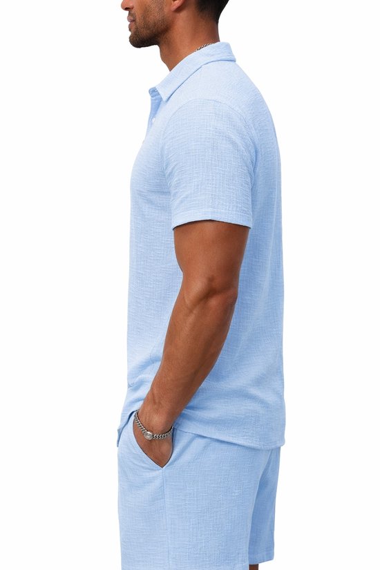 Man, zijaanzicht, draagt lichtblauwe korte mouw blouse en korte broek. Blouse met structuur.