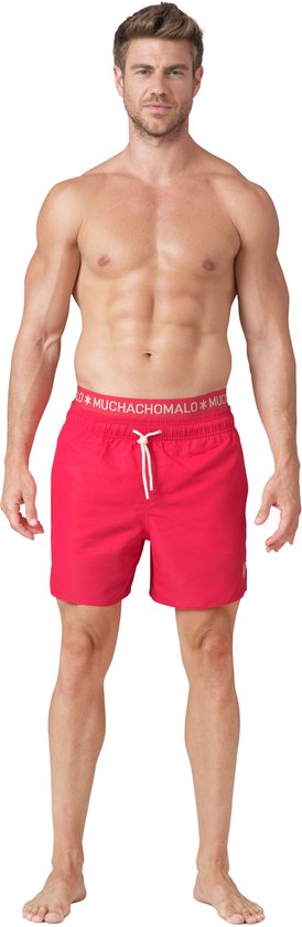 Man in rode zwembroek met witte tailleband met tekst 'MUCHACHOMALO'.