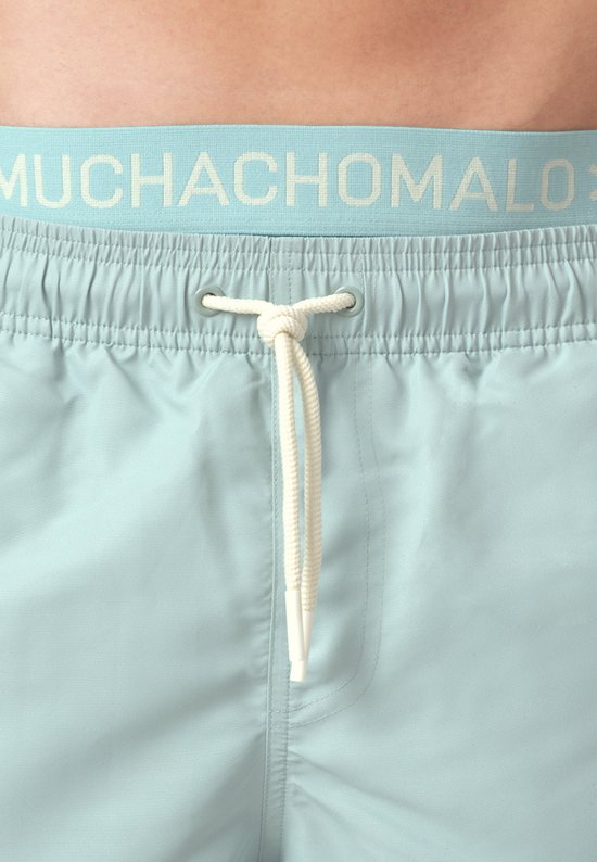 Lichtblauwe zwembroek met elastische tailleband en trekkoord. Op de band staat het logo 'MUCHACHOMALO'.