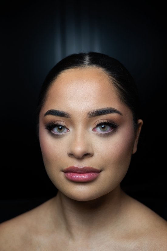 Model met een bruine ooglook en een subtiel groen/grijze kleurlens in haar linkeroog. Haar rechteroog is niet zichtbaar.