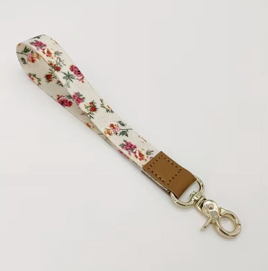 Bracelet de poignet blanc à imprimé floral rose et rouge, finition cuir marron et fermoir mousqueton argenté.