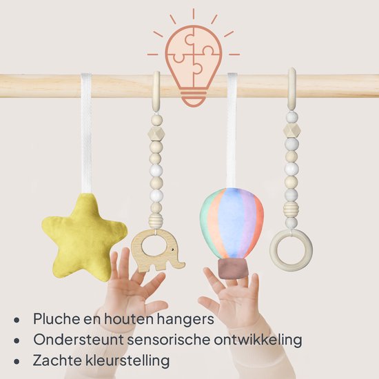Babyhandjes reiken naar zachte hangers aan een houten babygym: gele ster, houten olifant, gekleurde luchtballon.