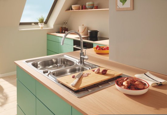 Zilverkleurige keukenkraan met hoge, gebogen uitloop in een keuken met mintgroene kasten en een dubbele spoelbak.