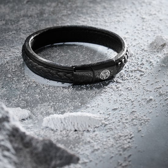 Zwarte gevlochten leren armband met zwarte magnetische sluiting met leeuwenlogo, op grijze ondergrond.
