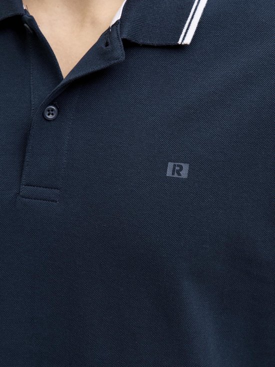 Close-up van donkerblauw poloshirt met witte kraag- en mouwstrepen en een 'R' logo.