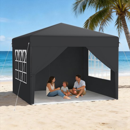 Zwarte partytent op een zandstrand, met een gezin dat op de grond zit, een palmboom en de oceaan op de achtergrond.