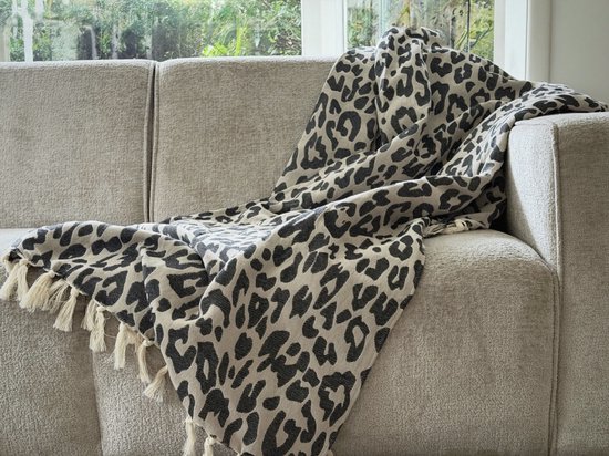 Grijze bank met een beige plaid met zwarte panterprint en witte franjes.