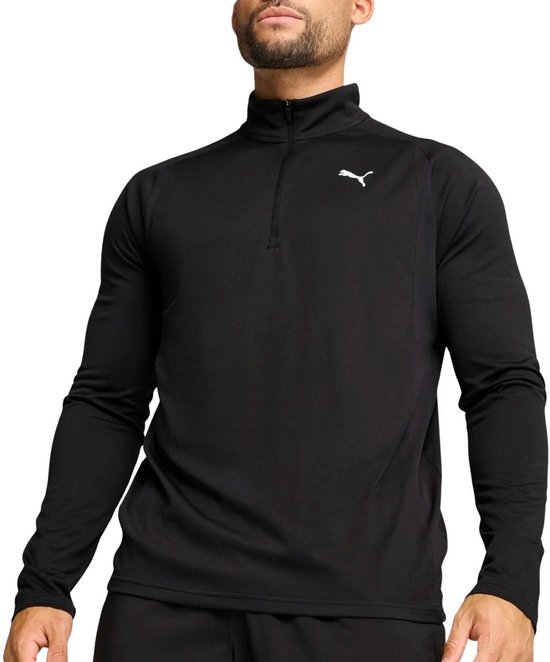 Man in zwart Puma trainingsjack met halve rits en opstaande kraag, met wit Puma-logo.