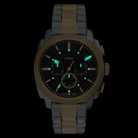 Gouden en zilverkleurig Fossil horloge met zwarte wijzerplaat en lichtgevende uurmarkeringen.