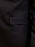 Detail van een zwarte blazer met klepzak.