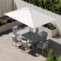 Rechthoekige witte parasol boven een tuintafel met zes stoelen, op een betegeld terras.