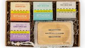 Rthink set met 4 zeepbars: Sunrise Radiance's Shampoo Bar (oranje), Ocean Whisper's Body Wash Bar (blauw), Alpine Mist's Face Wash Bar (grijs), Moonlit Wave's Conditioner Bar (paars). Inclusief houten zeephouder en sisal zakje.