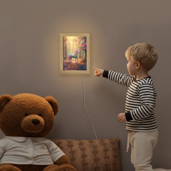 Een jongetje wijst naar een aan de muur hangende lamp met een eenhoorn in een bos.