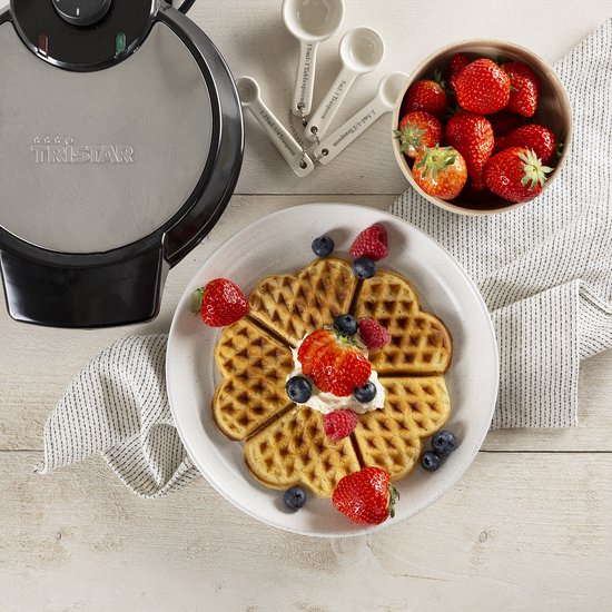 Gesloten zilverkleurig Tristar wafelijzer met hartvormige wafel versierd met fruit en slagroom.