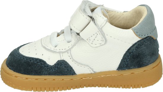 Zijaanzicht van een witte sneaker met blauwe suède onderdelen, klittenband en bruine zool.