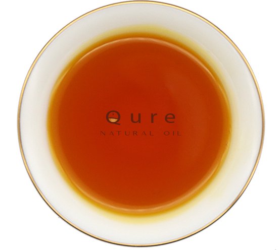 Schotel met gouden rand gevuld met Qure Natural Oil, oranje van kleur.