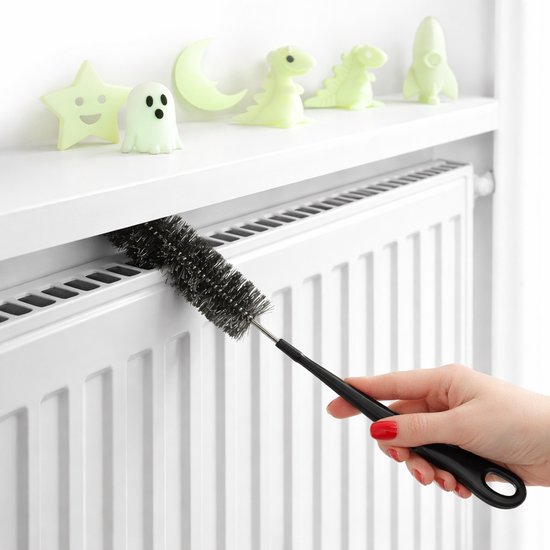 Zwarte radiatorborstel wordt gebruikt om een verwarming schoon te maken.