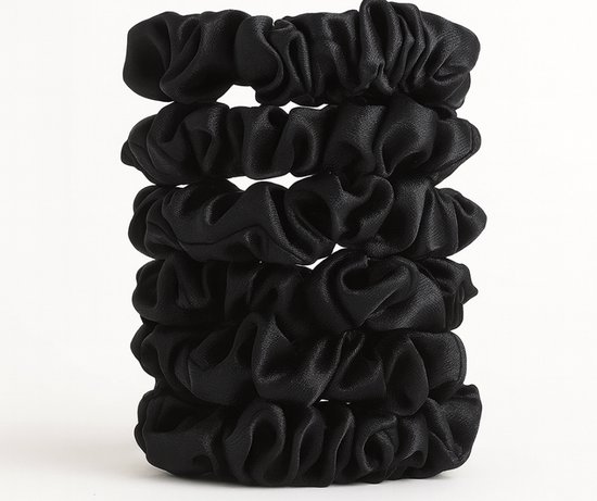 Stapel van vijf zwarte satijnen scrunchies op een witte achtergrond.