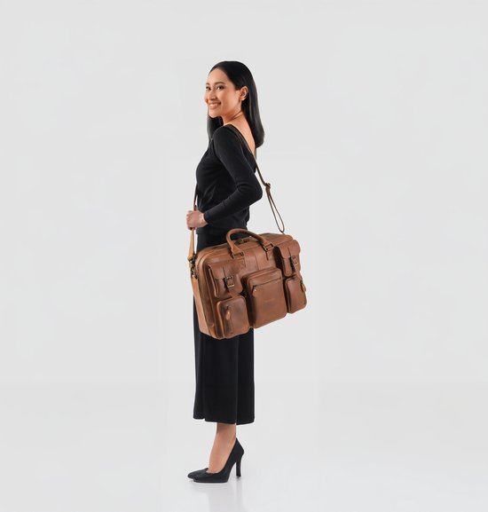 Vrouw met zwarte kleding draagt een bruine leren laptoptas over haar schouder.