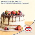 Een gelaagde chocolade- en vanillecake versierd met chocolade druppels, slagroom en verse bessen. Dr. Oetker logo.