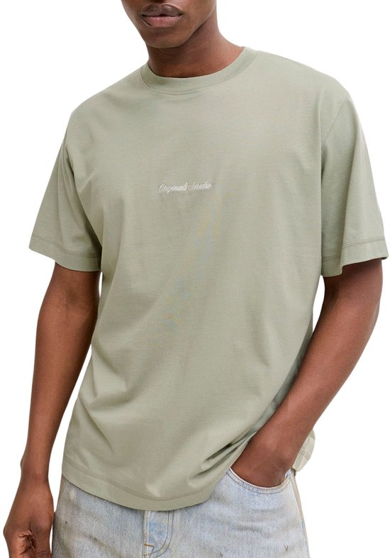 Homme portant un t-shirt vert clair avec la broderie 'Originals Studio'.