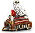 Grote witte LEGO uil op een stapel boeken met minifiguren en een rode edelsteen.