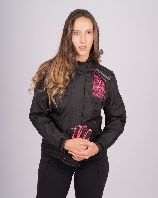 Vrouw met lange bruine haren draagt zwarte motorjas met roze accenten en roze handschoenen.