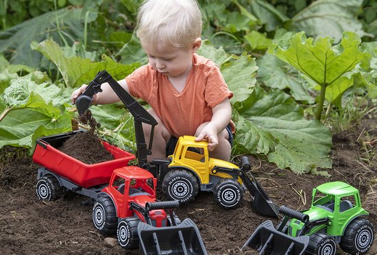 Jongetje van 1-2 jaar met blonde krullen speelt met speelgoed vrachtwagens: rode kipper, gele graafmachine, groene tractor.