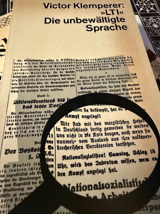 Une loupe est placée sur un journal allemand intitulé "Die unbewältigte Sprache", avec le nom de Victor Klemperer affiché de manière proéminente.