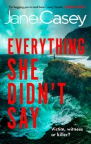 Boekomslag: Titel 'EVERYTHING SHE DIDN'T SAY' in rode letters op ruige zee en kliffen, met een klein figuur op een rots.