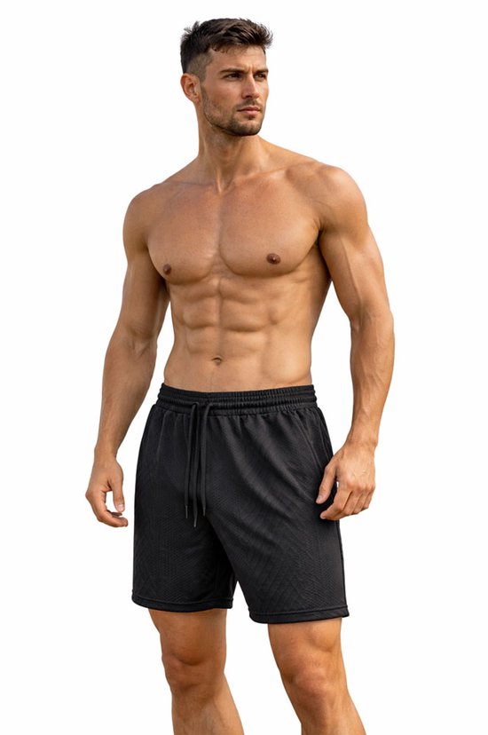 Man in een zwarte korte broek met trekkoord en een subtiel ruitpatroon, hand in de zak.