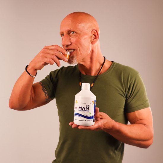 Een gespierde, kalende man met een groene t-shirt neemt een vitamine slice. Hij houdt een fles 'MAN MULTIVITAMIN' vast.
