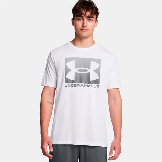 Wit sportshirt met groot grijs verloop logo en tekst 'UNDER ARMOUR' op de voorkant.