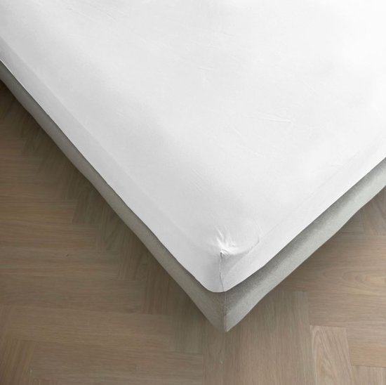 Strakke witte topperhoes op een bed, met een grijze rand aan de onderkant.