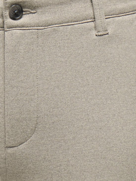 Detail van de tailleband van een beige chino met knoop en riemlussen.