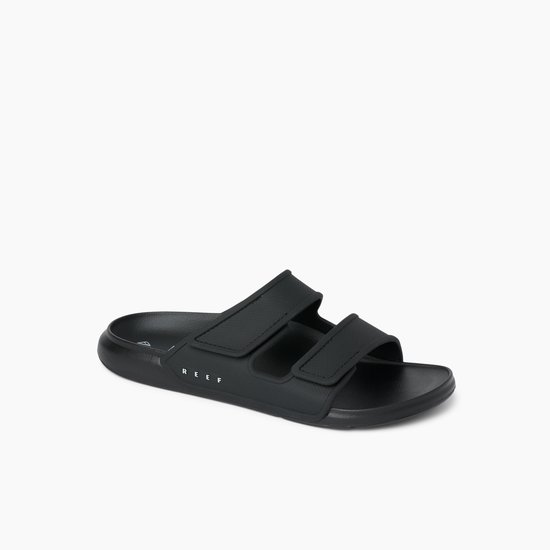 Zwarte Reef slipper met twee klittenbandsluitingen en reliëf textuur op de banden.