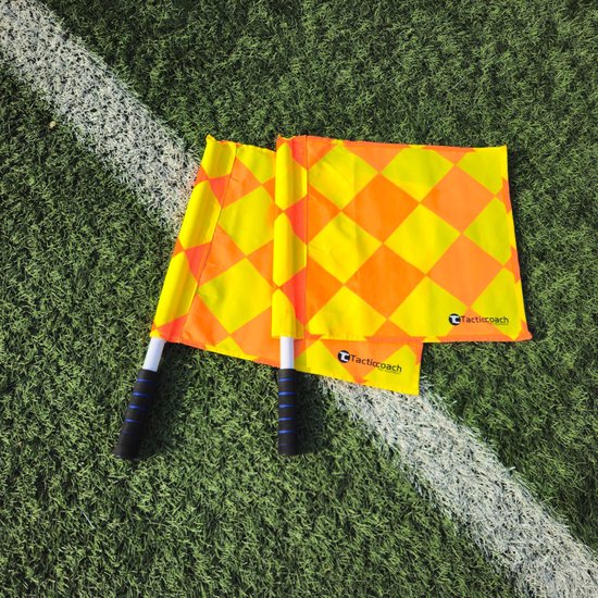 Twee grensrechtervlaggen met een ruitpatroon van geel en oranje, liggend op een voetbalveld.