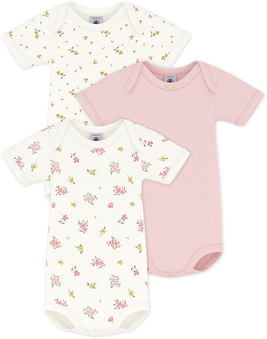 Trois barboteuses en coton pour bébé. Une rose unie, une blanche à imprimé floral jaune, une blanche à imprimé floral rose.