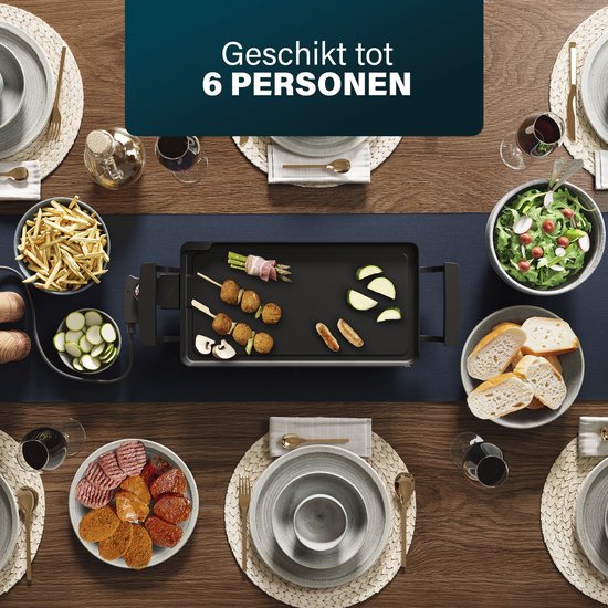 Zwarte grillplaat met eten voor 6 personen, inclusief worstjes, groenten en aardappelfrietjes.