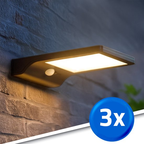 Zwarte solar wandlamp op een stenen muur, met de tekst '3x' in een blauwe cirkel.