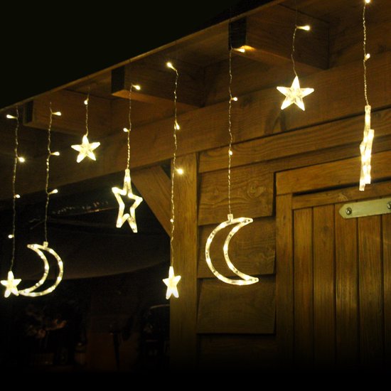 Gordijn met warm witte LED-lichtjes in de vorm van manen en sterren, hangend aan een gebouw.